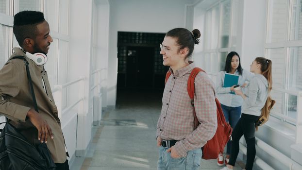 Group of students is standing in big spacious corridor girl are talking and laughing at university