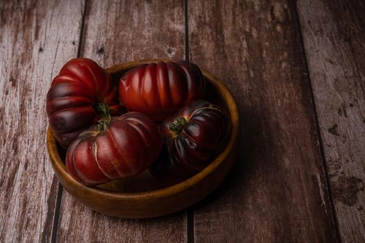 group of moorish tomatoes in a wooden bowl isolated on a wooden table