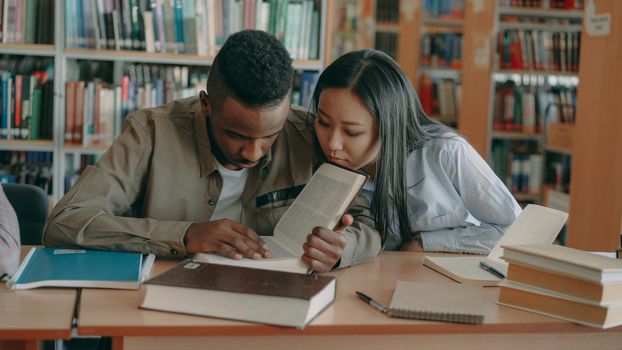 diligent biracial students preparing for exams doing homework in college library