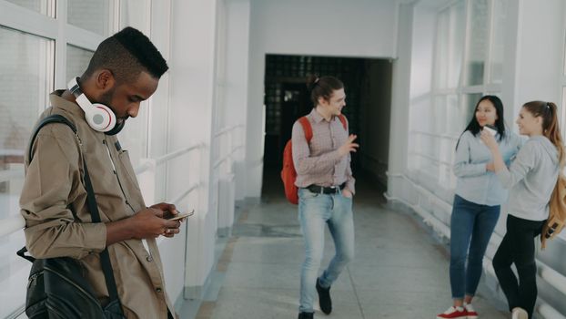 Group of students is standing in big spacious corridor girl are talking and guy waving hand