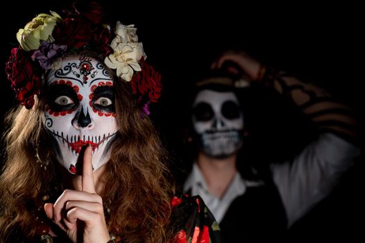 Man and woman in paired halloween costumes. Body art santa muerte and skeleton.