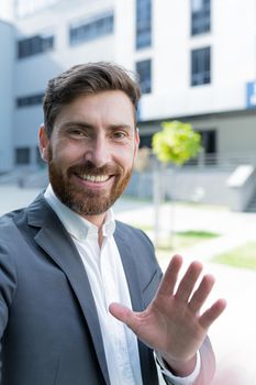 vertical view smartphone camera Caucasian bearded businessman speaks on phone using a front camera on a video call. employee business man talking on webcam. Conversation of an office worker in suit