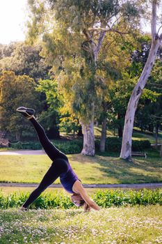 vertical photo of a young sports woman doing meditation yoga balancing exercises and relaxing outdoors in the park, modern healthy lifestyle and sport concept