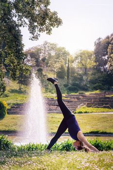 vertical photo of a young sports woman doing meditation yoga exercises and relaxing outdoors in the park, modern healthy lifestyle and sport concept