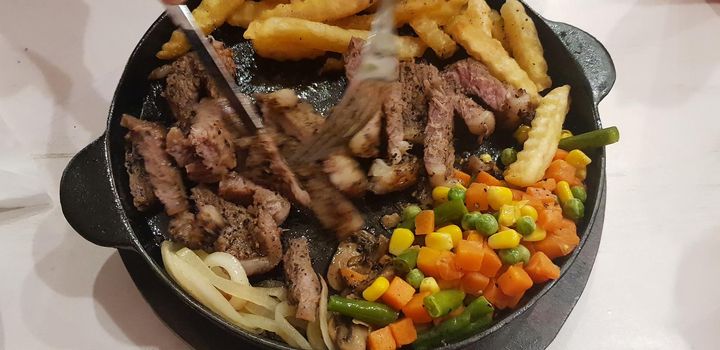 The best food in the world beef steak along with fried potatoes with delicious mushroom sauce and salad and spaghetti plated in beautiful black plate