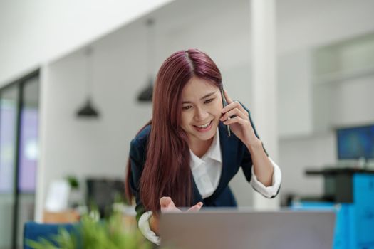 Asian businesswoman using the phone to contact a business partner.