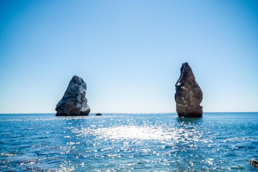 Two rocks stick out of the water in the middle of the turquoise sea. Scenic ocean views. High quality photo. Like in Iceland.