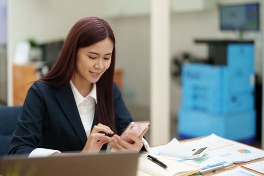 Asian businesswoman using the phone to contact a business partner..