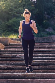 young sporty girl running downstairs in the morning on the stairs of the park, morning workout outdoors, sports and healthy lifestyle