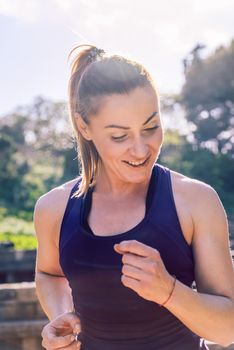 vertical portrait of happy sports woman running during outdoor workout at the park at the morning with sunlight, sport and healthy lifestyle concept