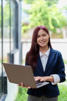 Portrait of a smiling Asian businesswoman holding a computer.