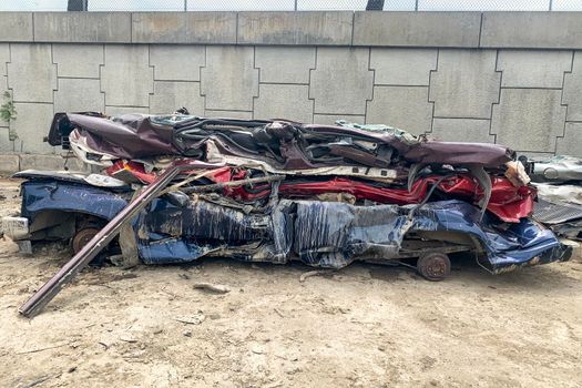 A pile of compressed cars going to be shredded, crushed junk vehicles on scrapyard
