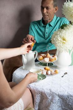 tea break in the English style, still life with flowers and donuts in the morning sun, homemade cakes, married couple drinking tea together at breakfast in english style, beautifully set table