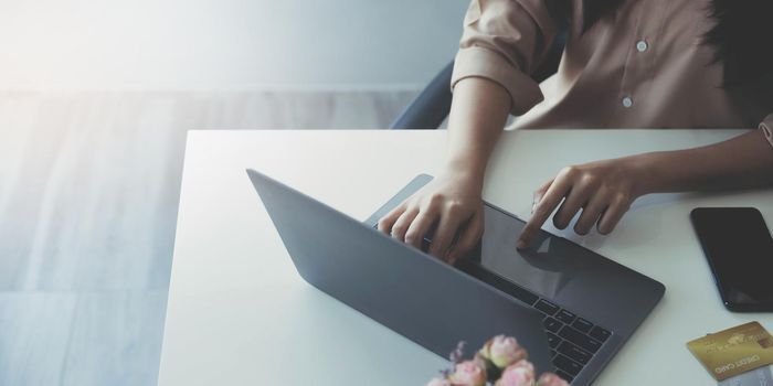 Close-up of female hands using laptop at office, woman's hands typing on laptop keyboard in interior,, side view of businesswoman using computer in office