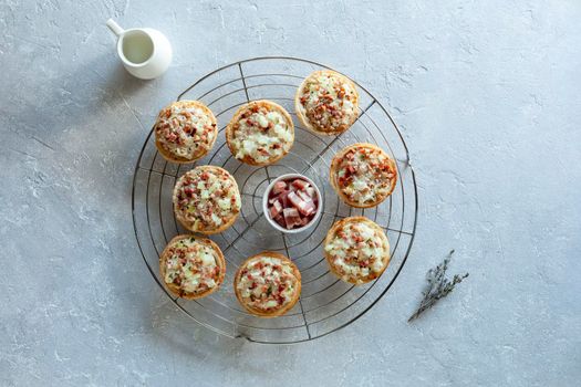 mini portions of flammekueche, or tarte flambee, french and german speciality, on the metal round cooling grid, top view