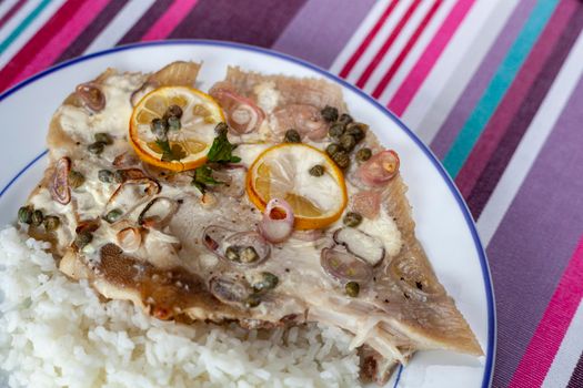 ray fish wings prepared with capers, shallot and lemons and served with rice, top view