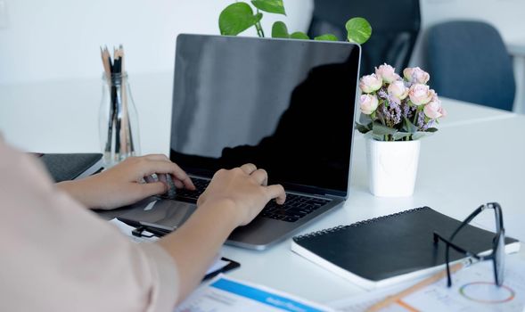 Side view of a businesswoman working on a laptop blank black screen at office