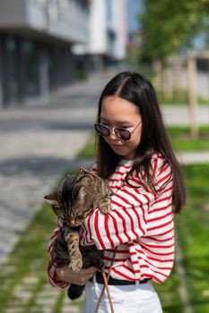 Young woman holding tabby cat in her arms outdoors