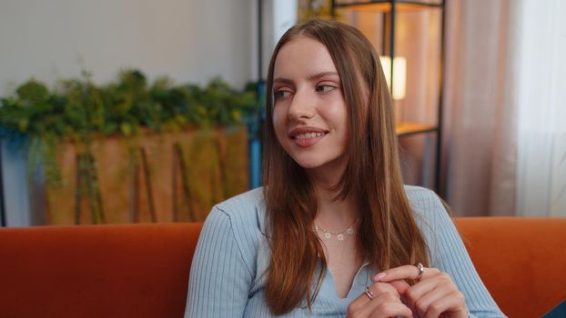 Close-up of happy calm young woman smiling friendly glad expression looking away dreaming resting, relaxation feel satisfied concept good news sitting on sofa at home room. Pretty girl falling in love