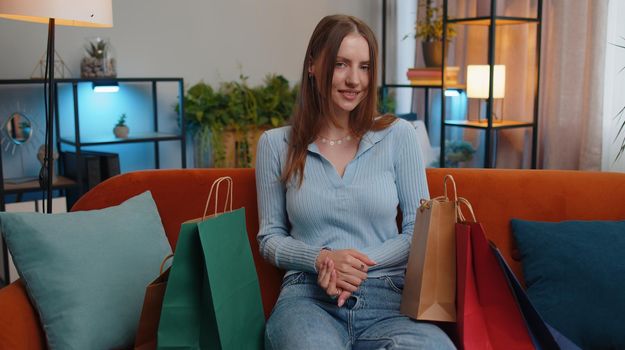 Young woman happy shopaholic consumer came back home after shopping sale with bags. Pretty girl shopper satisfied received parcels presents from online order at modern apartment. Holiday sale discount