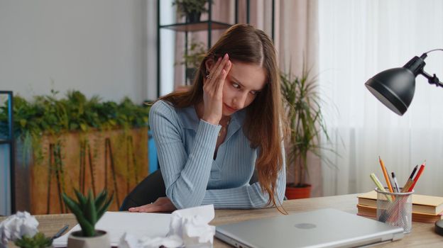 Tired woman freelancer teacher using laptop computer, suffering from tension, migaine headache after e-learning, remote working job with pupils sitting at home office table. Adult girl businesswoman
