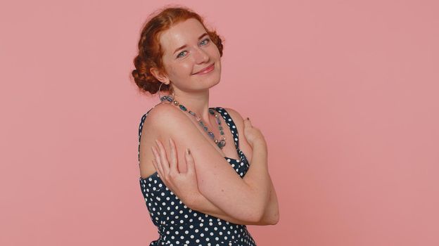 Come to me, I want to embrace you. Young redhead woman in dress spread hands and give hug to you. Pleasant expression, love feelings. Ginger girl with freckles isolated alone on pink studio background