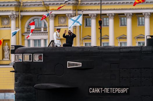 Russia, St. Petersburg, 31 July 2022: The commander of a submarine standing in the center of the city looks through binoculars, he is dressed in a festive white uniform, celebration of the day of Navy. High quality photo