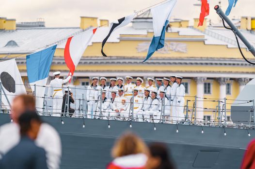 Russia, St. Petersburg, 31 July 2022: Military sailors dressed in festive uniforms take a group photo with the commander on the deck of a warship next to a huge cannon, the celebration the Navy Day. High quality photo