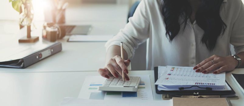 Close-up of businesswoman hands using a calculator to check company finances and earnings and budget. Business woman calculating monthly expenses, managing budget, papers, loan documents, invoices..