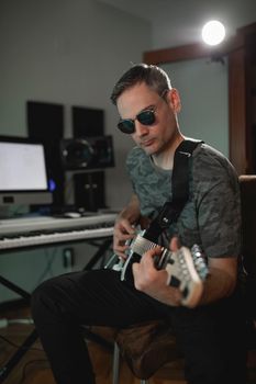 Music producer strumming some chords with the electric guitar while recording a new project at his home studio