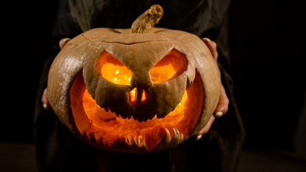 The witch is holding a pumpkin jack about a lantern glowing in the dark. Halloween