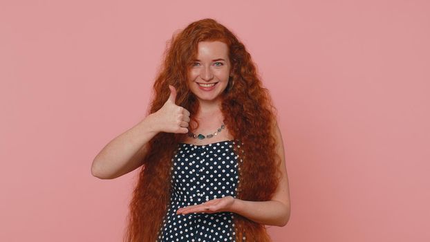 Look at advertisement. Subscribe. Redhead woman pointing down, saying to follow link, gesturing ok and like, showing place for commercial, promotional information below. Ginger girl on pink background