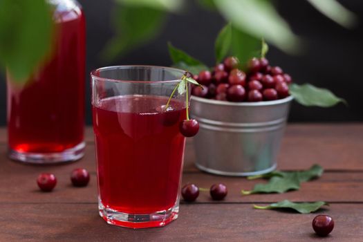 cherry juice in a glass with cherries on a wooden background