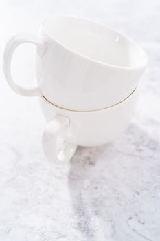 White ceramic cups prepared to bake chocolate mug cakes.