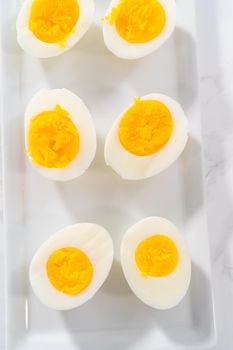 Sliced hard-boiled eggs on a white serving plate.