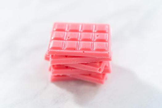 Stack of homemade mini pink chocolates on the counter.