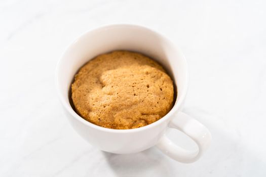 Freshly made to prepare pumpkin mug cake in a large white mug.