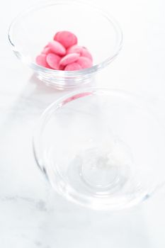 Ingredients in glass mixing bowls to make mini pink chocolates.