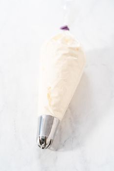 Homemade whipped cream in a piping bag with a metal tip.