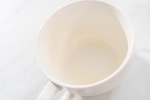 Pouring cake batter into the mug to prepare pumpkin mug cake.