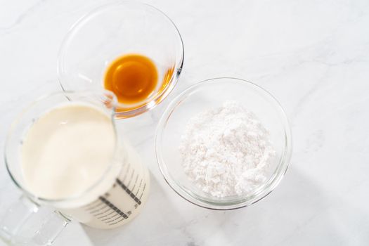 Measured ingredients in glass mixing bowls to prepare the homemade whipped cream.