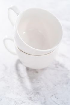 White ceramic cups prepared to bake chocolate mug cakes.