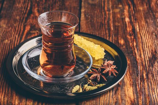 Oriental glass with Spiced tea and navad on metal tray over wooden surface