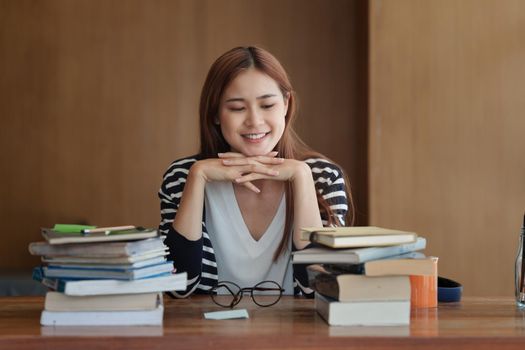 Back to school concept. Young college woman reading book at library.