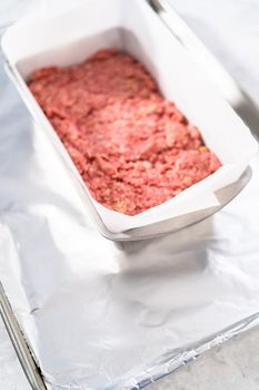 Preparing classic meatloaf in a loaf pan lined with parchment paper.