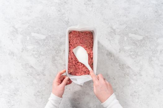 Flat lay. Preparing classic meatloaf in a loaf pan lined with parchment paper.