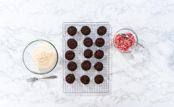 Flat lay. Dipping chocolate cookies into the melted white chocolate to prepare peppermint white chocolate cookies.