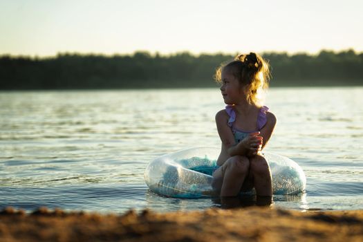 Little girl on the beach sits in the water on an inflatable ring. High quality photo
