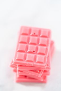 Stack of homemade mini pink chocolates on the counter.