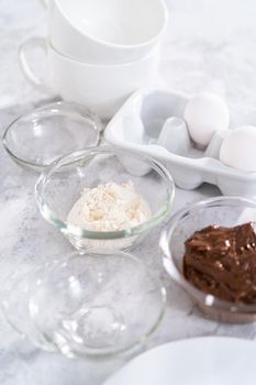 Ingredients in glass mixing bowls to prepare chocolate mug cakes.